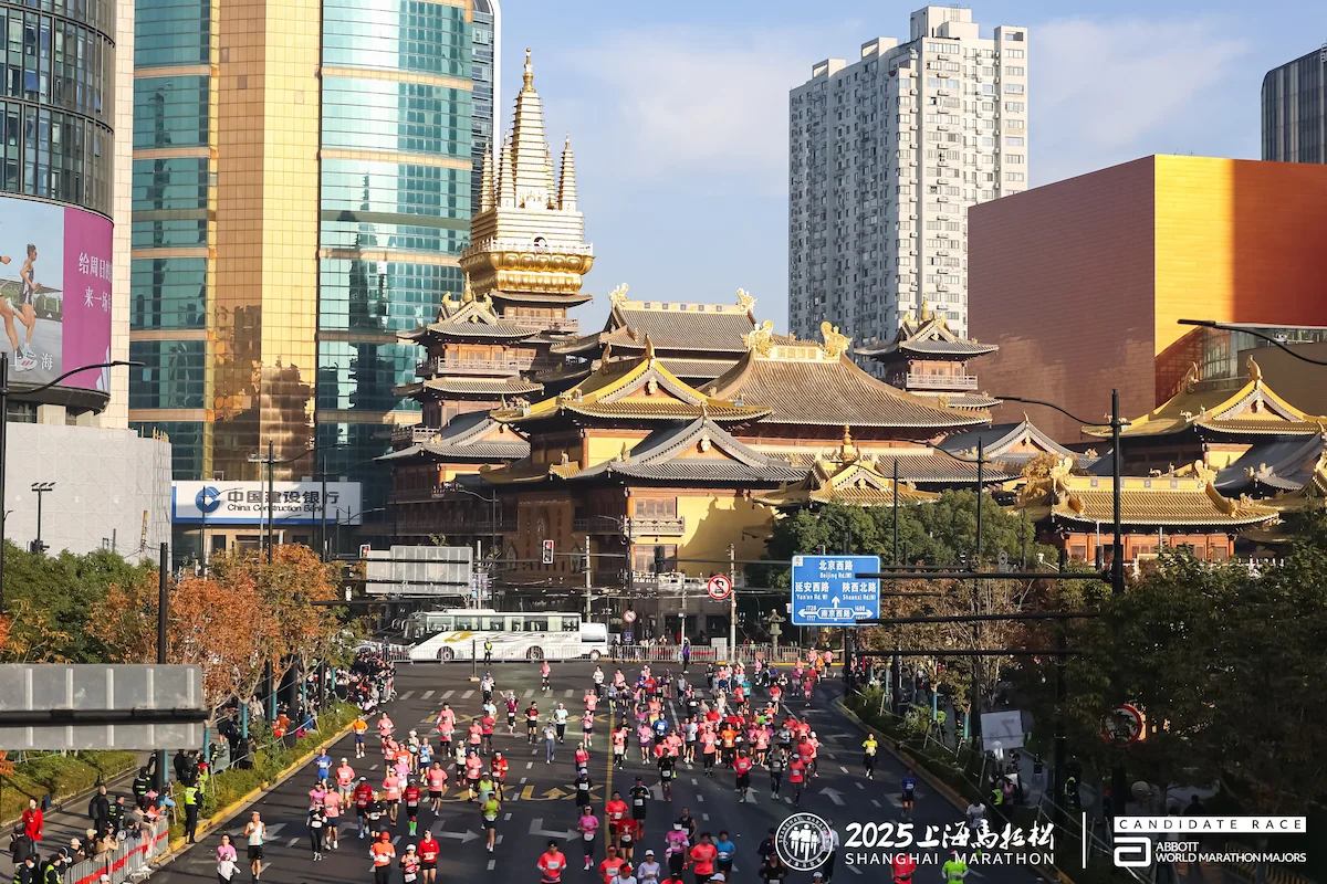 Corredores del Shanghai Marathon por una avenida de Shanghái junto a arquitectura tradicional