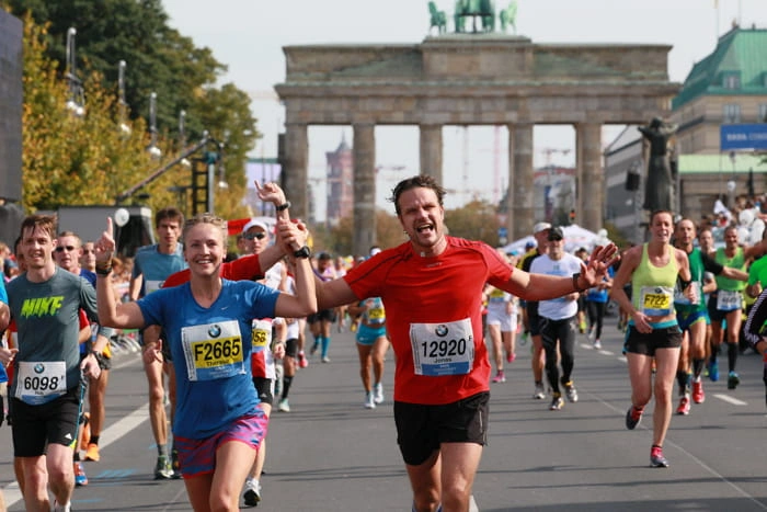 Dos corredores de GeoSport celebrando el éxito en un maratón, ilustrando la cercanía y el asesoramiento personalizado del equipo.